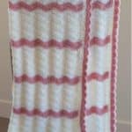 pink and white crochet baby blanket hanging over chair with text baby blanket crochet pattern