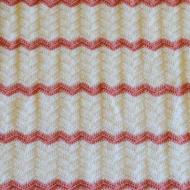 pink and white crochet baby blanket folded