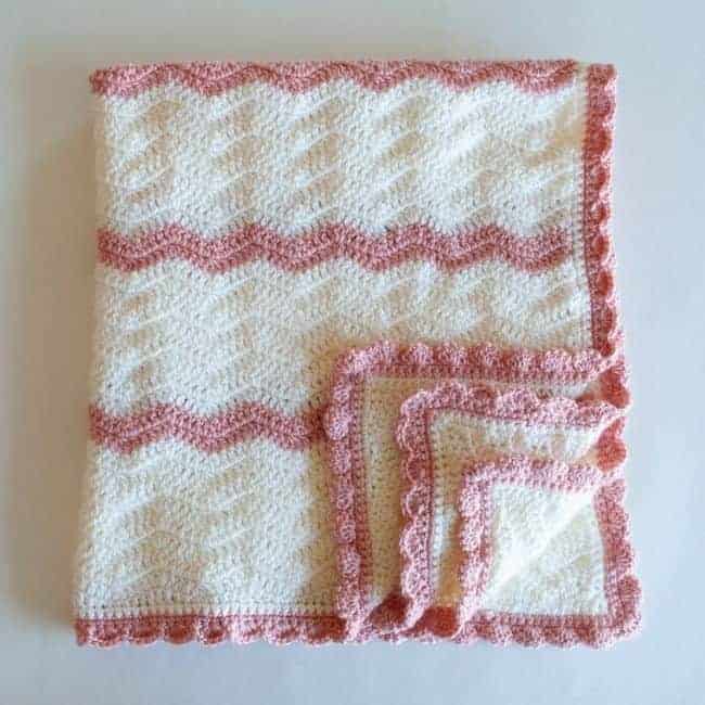 pink and white crochet baby blanket folded