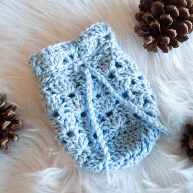 blue small crochet gift bag lying flat next to pine cones