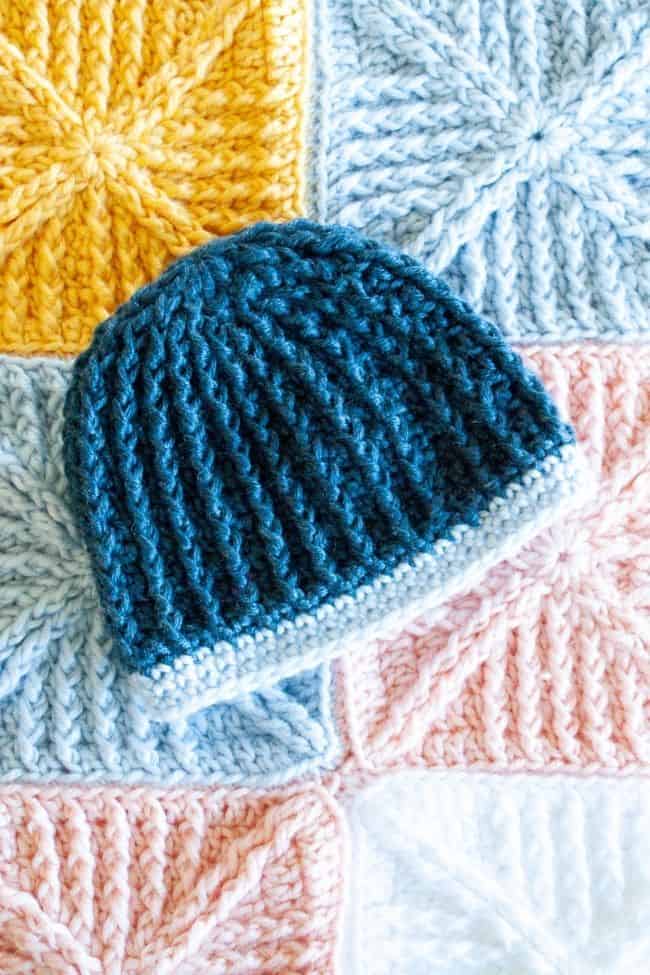 blue crochet baby hat on a crochet baby blanket