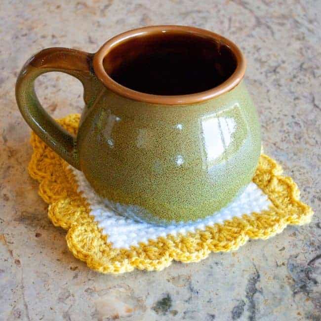 white and yellow square crochet coaster with green mug
