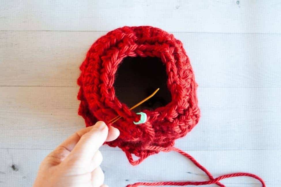 top of crochet hat with hole at top tapestry needle being inserted