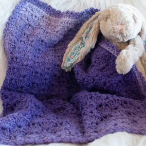 stuffed bunny holding a purple ombre yarn crochet security blanket