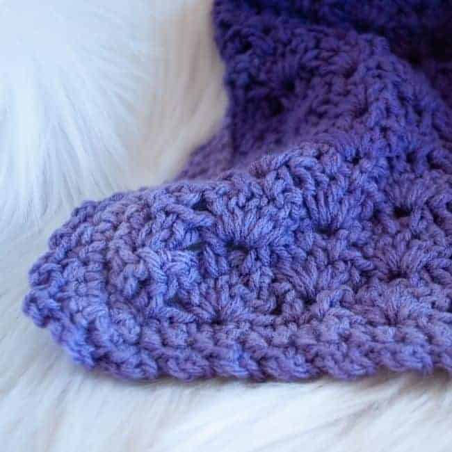 close up of corner of purple baby blanket showing border
