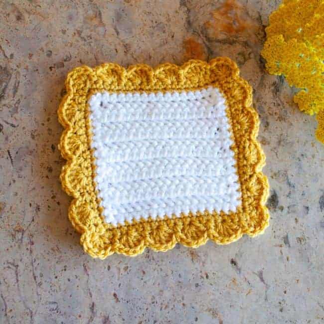 white square crochet coaster with yellow shell border