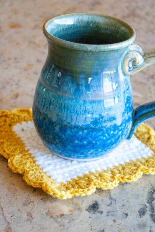square white and yellow crochet coaster with blue mug