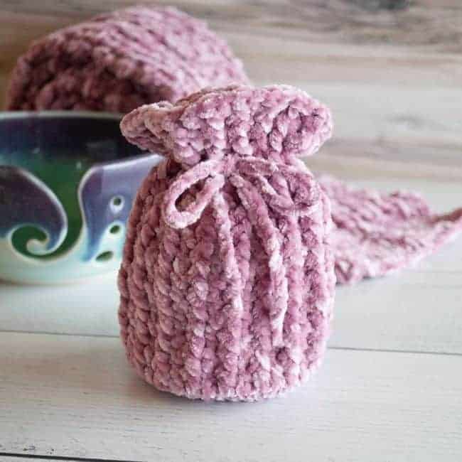 velvet yarn crochet gift bag with yarn bowl and scarf rolled up in background