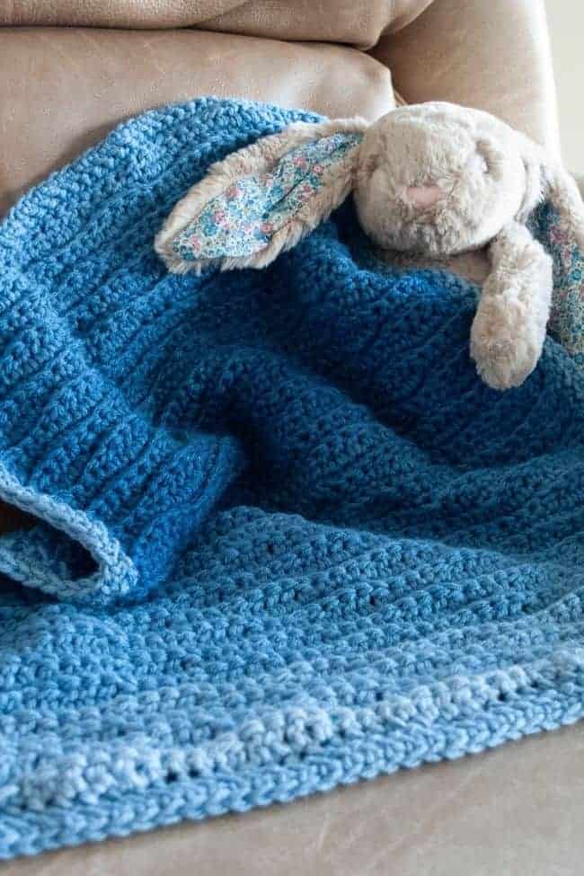 stuffed rabbit holding blue ombre crochet blanket