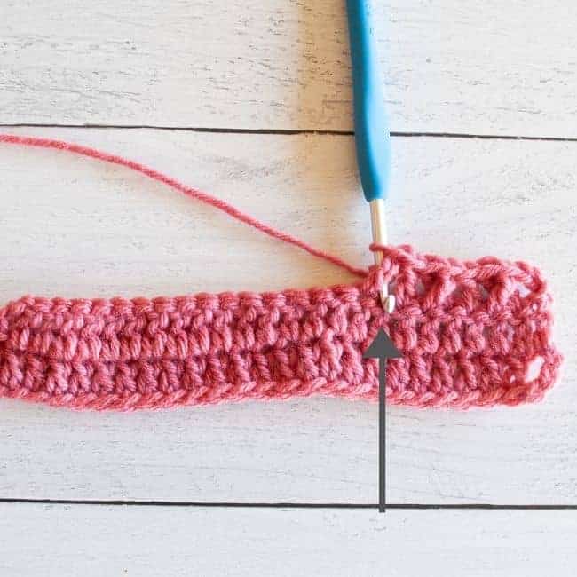 yarn over and inserting the hook behind the first double crochet with arrow indicating location for second double crochet