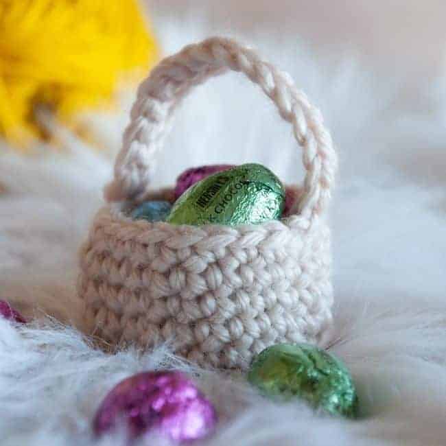 mini crochet easter basket holding chocolate eggs with ball of yarn in background