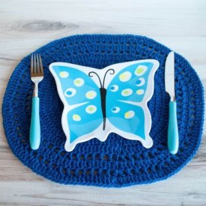 blue crochet oval placemat with fork knife and butterfly plate on top