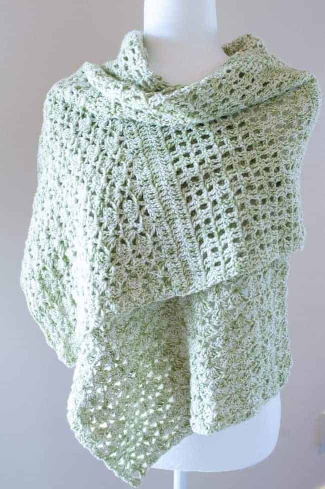 green lightweight crochet shawl draped on a mannequin