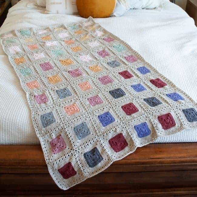 scrap yarn blanket draped on a bed
