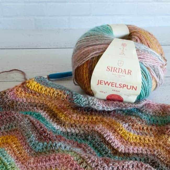 ball of jewelspun yarn with crochet ripple shawl in progress and hook