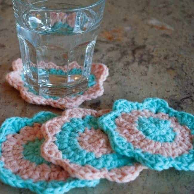 glass of water on a crochet coaster and three more coasters