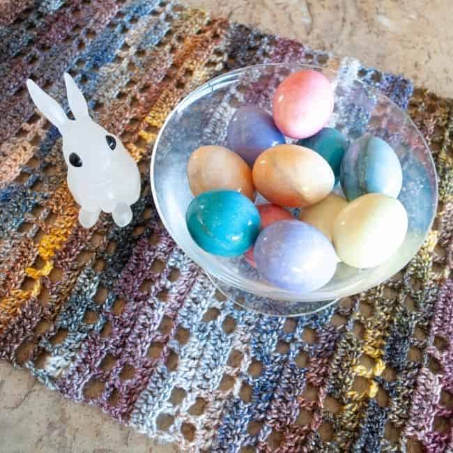 close up of crochet table runner with a bunny and bowl of eggs on it