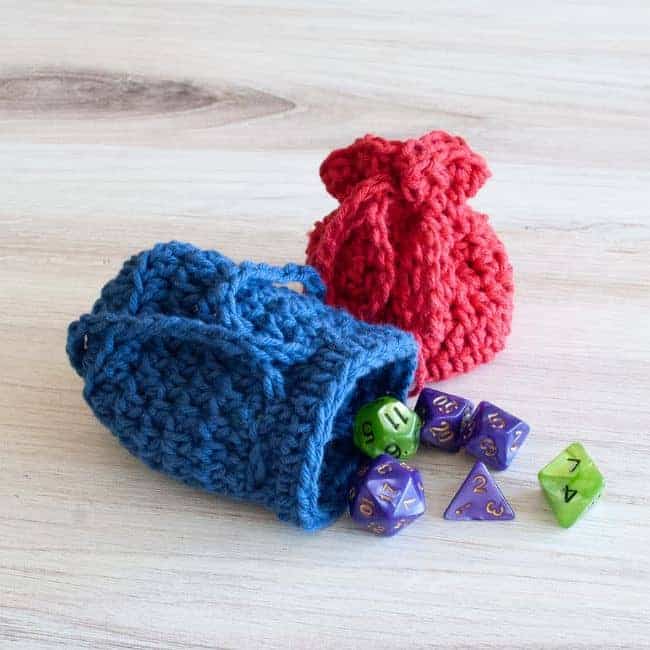 blue crochet dice bag with dice spilling out and red dice bag tied closed