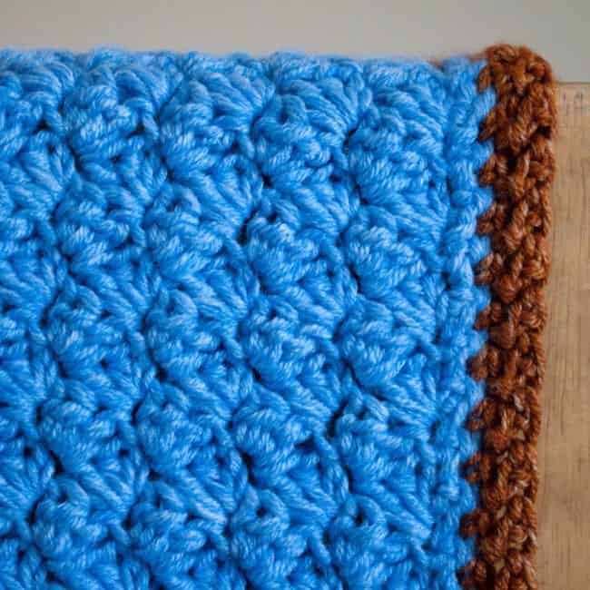 close up of sedge stitch in blue yarn with a border in another stitch