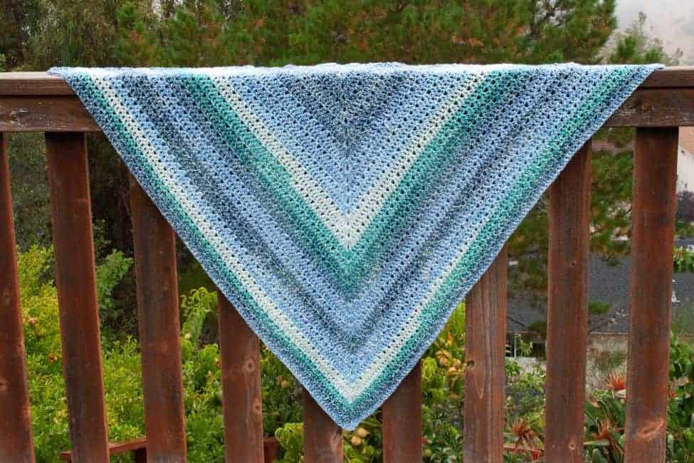 triangle crochet shawl hanging spread out on a fence