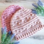 two pink womens crochet beanies with purples flowers