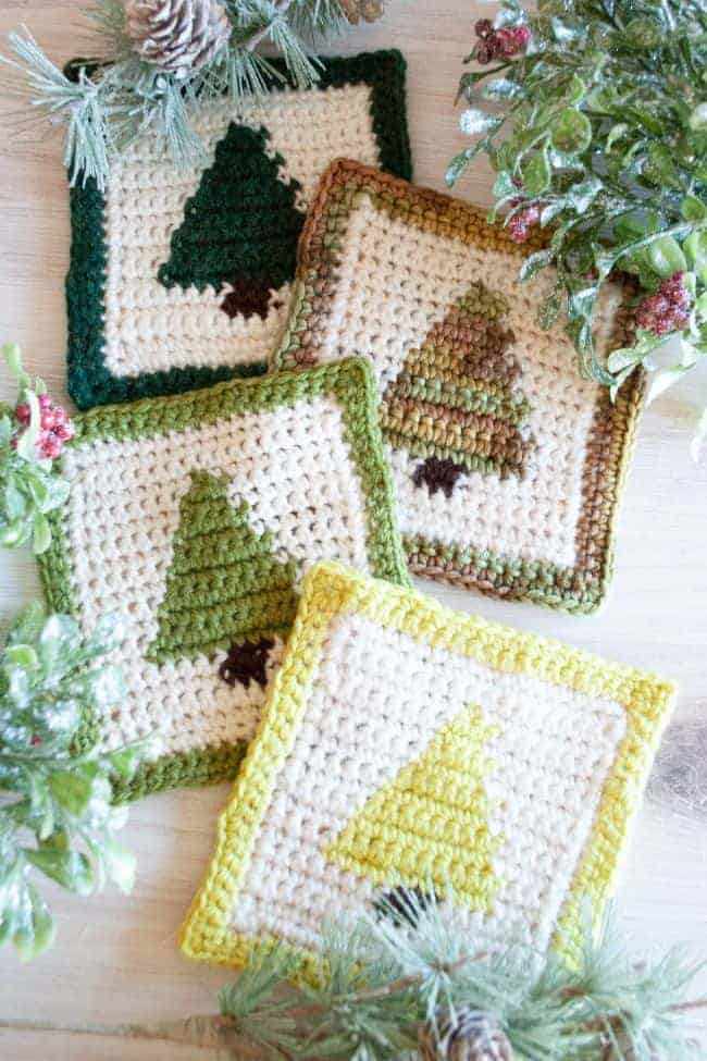 four christmas tree crochet coasters with greenery