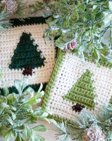 two christmas tree crochet coasters and greenery