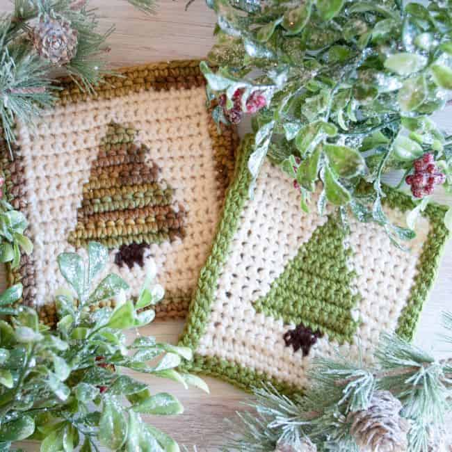 two christmas tree crochet coasters with greenery
