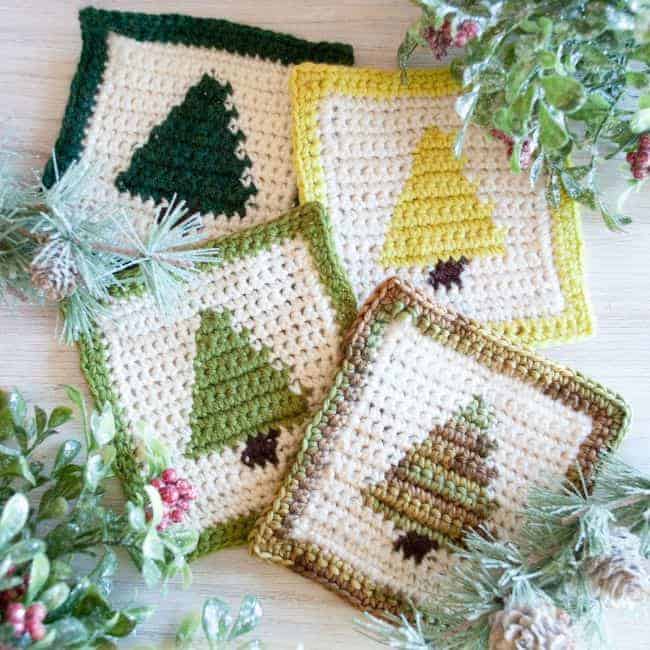 four christmas tree crochet coasters with greenery