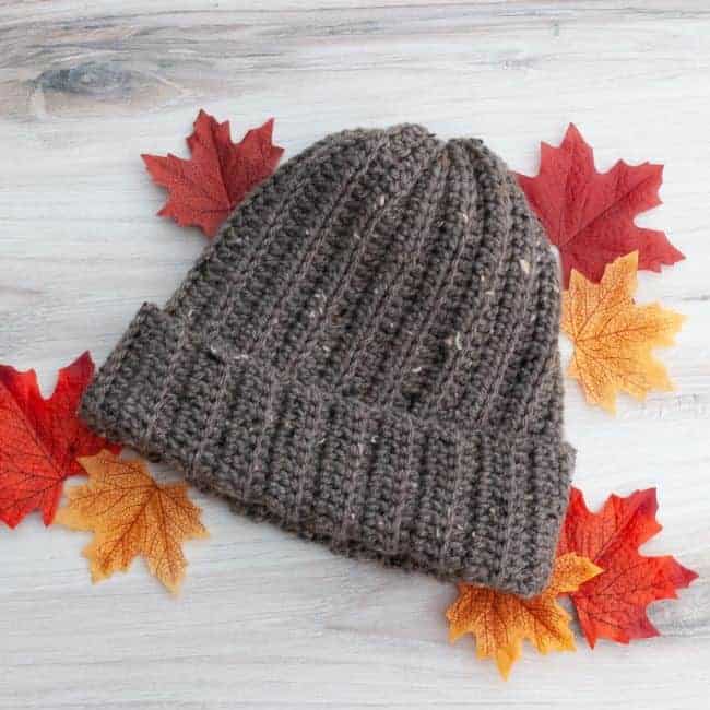 mens crochet beanie lying flat on a table with fall leaves