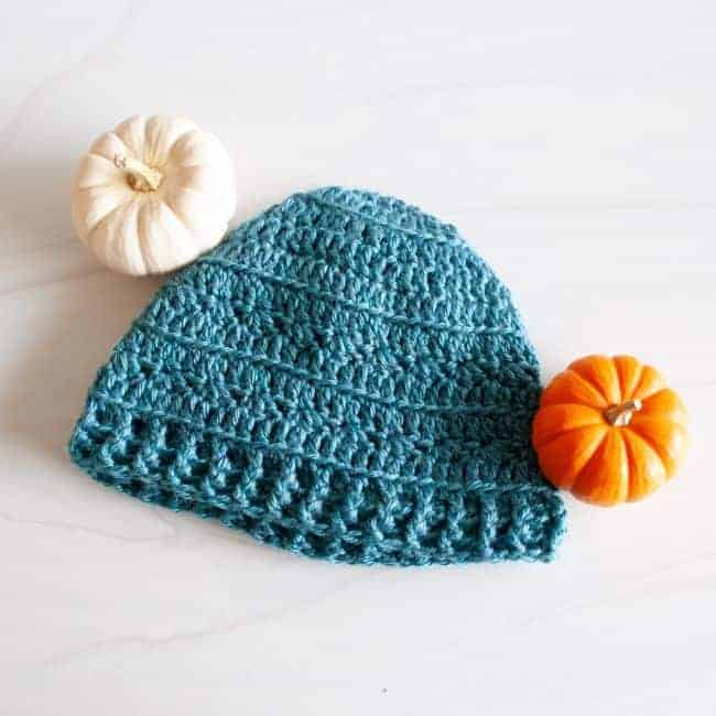teal crochet hat and two small pumpkins